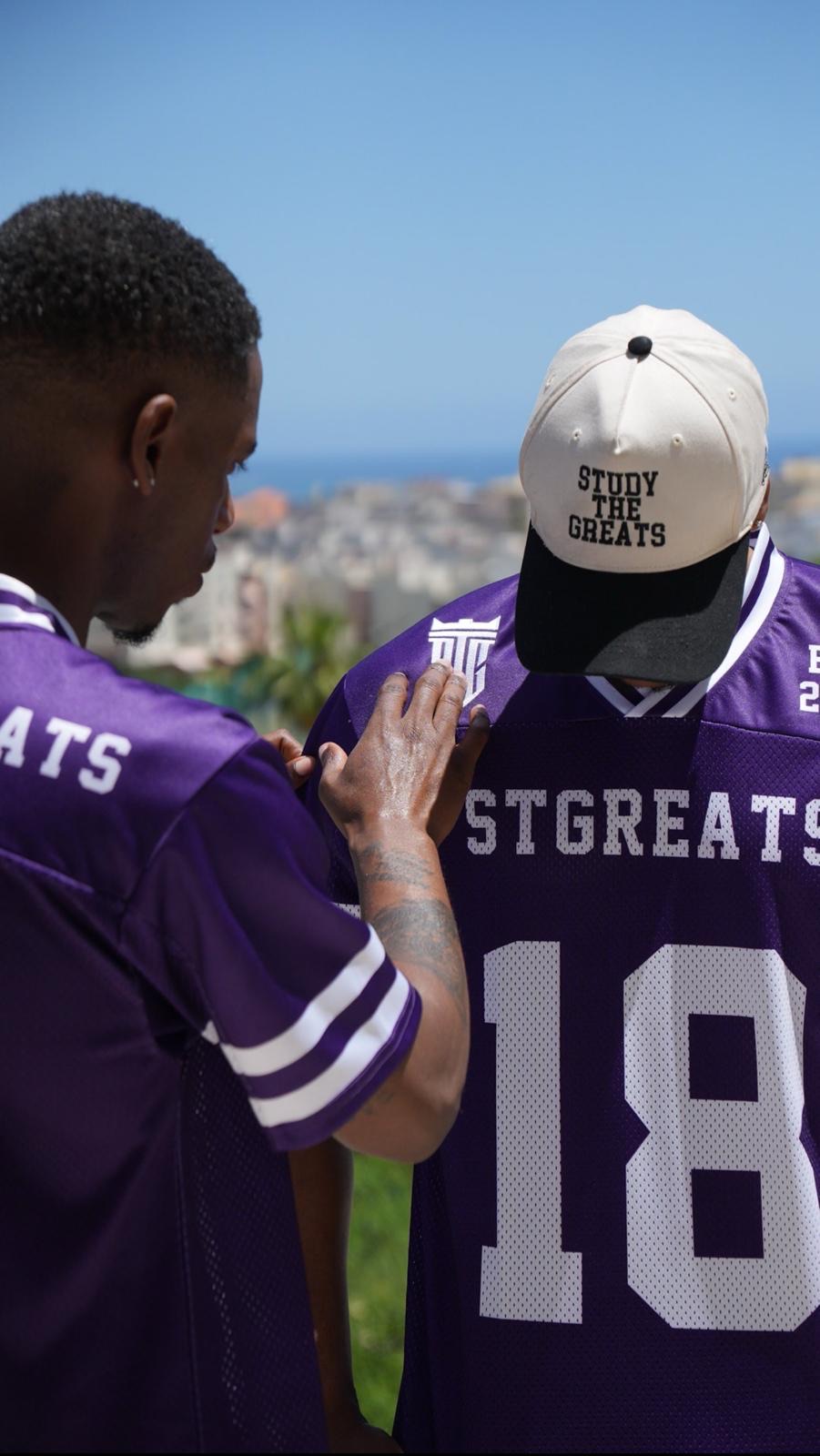 Two men wearing purple Study The Greats jerseys and a branded cap